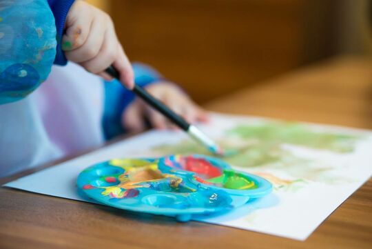 Enfant avec un tablier bleu faisant de la peinture